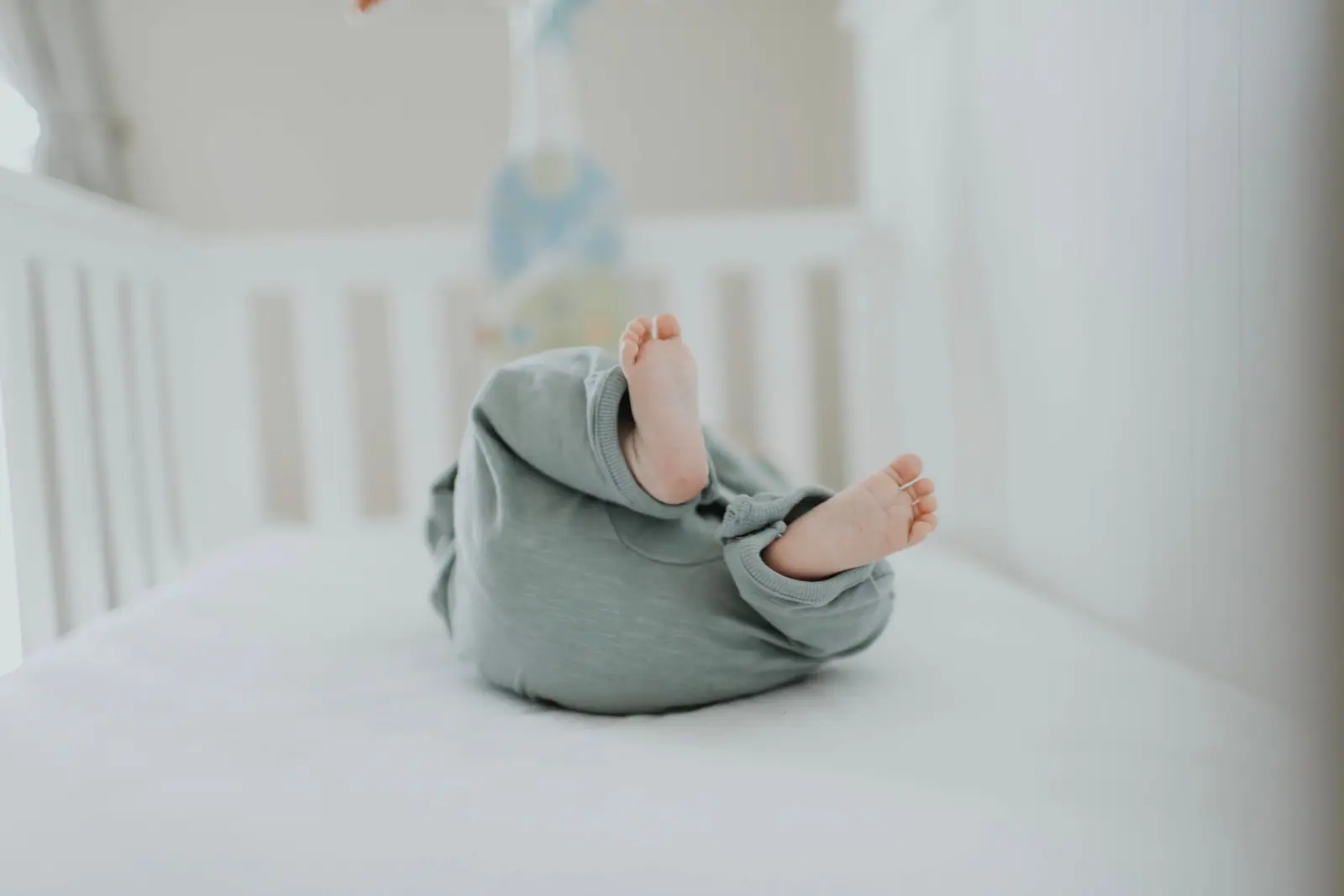 A baby lying in a crib on a bare fitted sheet