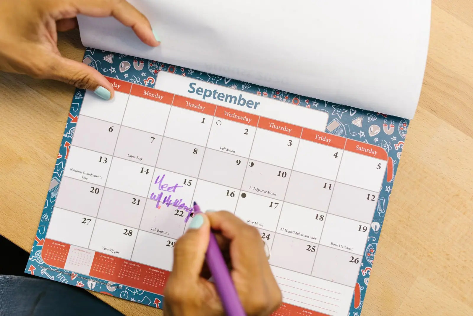 A hand writing on a paper monthly calendar