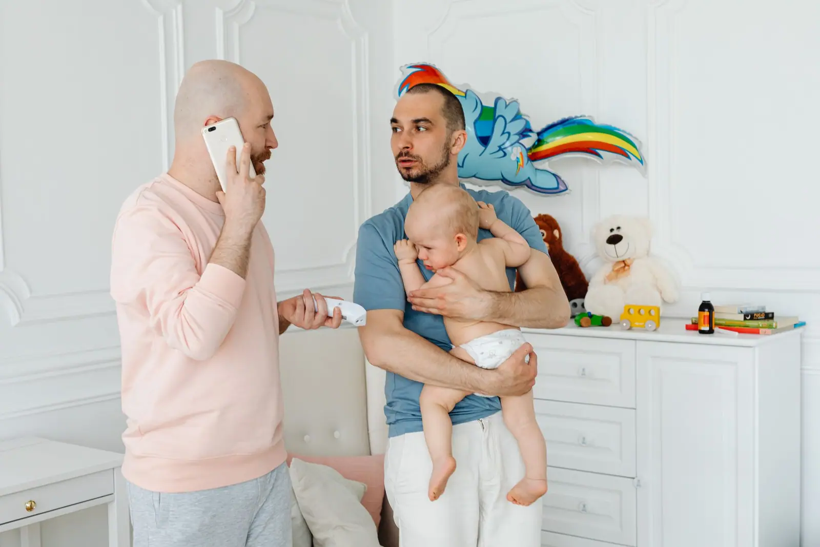 A parent holding a smartphone beside their face while another holds a baby